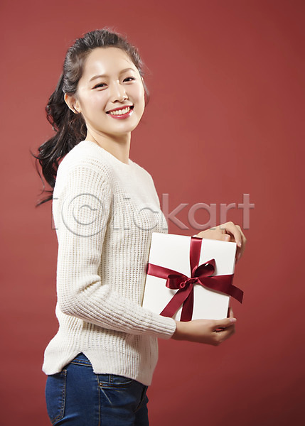 따뜻함 사랑 행복 20대 사람 성인 성인여자한명만 여자 한국인 한명 JPG 옆모습 포토 들기 리본 미소(표정) 빨간배경 상반신 선물 선물상자 스튜디오촬영 실내 여대생 응시 의료성형뷰티