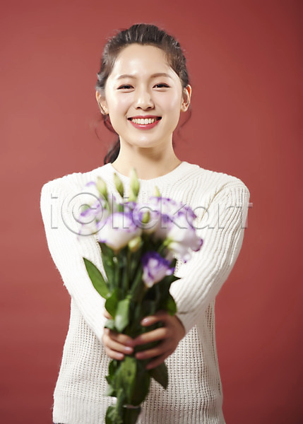 즐거움 행복 20대 사람 성인 성인여자한명만 여자 한국인 한명 JPG 앞모습 포토 꽃 꽃다발 들기 미소(표정) 빨간배경 상반신 손내밀기 스튜디오촬영 실내 여대생 응시 의료성형뷰티