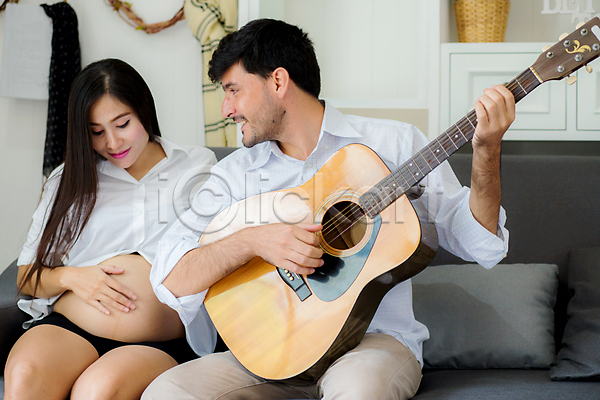 사랑 남자 동양인 두명 백인 성인 성인만 여자 JPG 앞모습 포토 해외이미지 기타 기타리스트 듣기 들기 미소(표정) 부부 상반신 실내 앉기 연주 임신