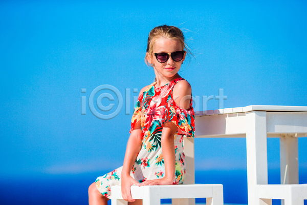 휴식 소녀(어린이) 소녀한명만 어린이 여자 한명 JPG 옆모습 포토 해외이미지 꽃무늬 미코노스섬 바캉스 상반신 선글라스 앉기 야외 여름(계절) 여름휴가 원피스 의자 주간 탁자 파란색 하늘