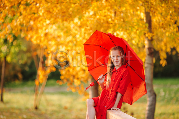 소녀(어린이) 소녀한명만 어린이 여자 한명 JPG 아웃포커스 옆모습 포토 해외이미지 가을(계절) 공원 미소(표정) 빨간색 상반신 앉기 우산