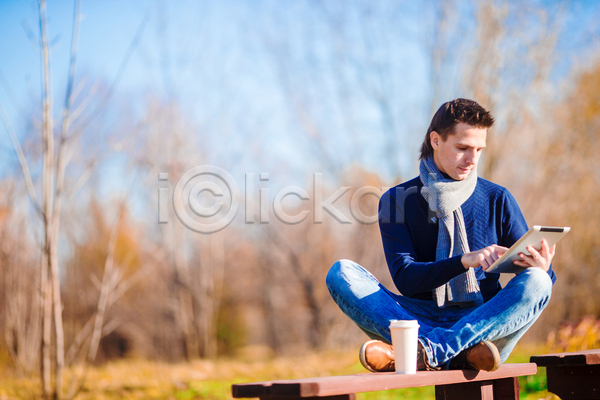 남자 성인 성인남자한명만 한명 JPG 포토 해외이미지 가을(계절) 가을풍경 공원 미소(표정) 숲 앉기 야외 응시 잡기 커피 컵 태블릿