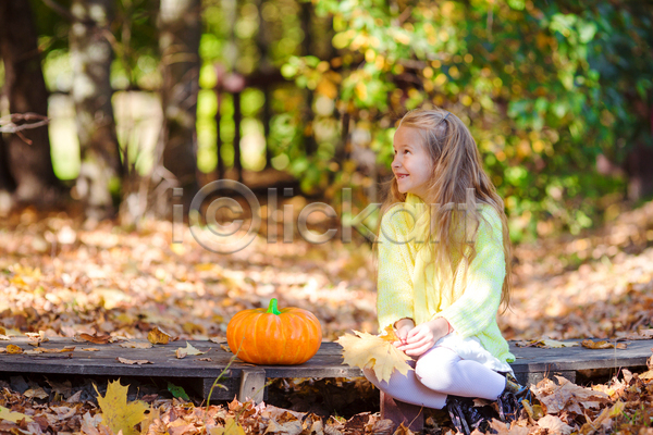 소녀(어린이) 소녀한명만 어린이 여자 한명 JPG 아웃포커스 앞모습 포토 해외이미지 가을(계절) 공원 낙엽 단풍 들기 미소(표정) 앉기 올려보기 전신 호박