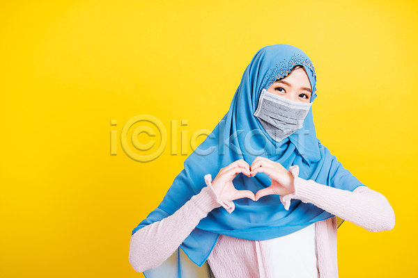 사랑 행복 동양인 성인 성인여자한명만 여자 한명 JPG 앞모습 포토 해외이미지 노란색 마스크 상반신 손하트 이슬람교 하늘색 하트 히잡