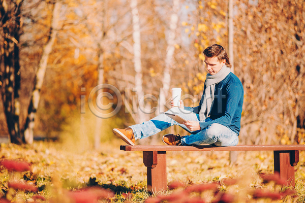 남자 성인 성인남자한명만 한명 JPG 아웃포커스 옆모습 포토 해외이미지 가을(계절) 공원 낙엽 들기 벤치 앉기 응시 전신 태블릿 테이크아웃컵