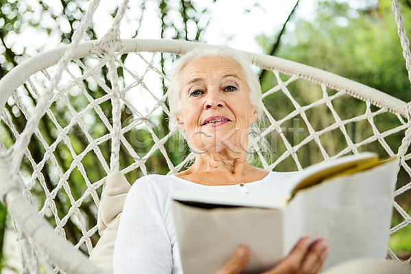 여유 즐거움 60대 노년 노인여자한명만 사람 서양인 성인 여자 외국인 한명 JPG 로우앵글 앞모습 포토 그네 독서 들기 백발 상반신 실버라이프 앉기 야외 여름(계절) 주간 책 체코 캐주얼 평생교육 할머니