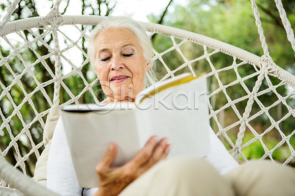 여유 즐거움 60대 노년 노인여자한명만 사람 서양인 성인 여자 외국인 한명 JPG 로우앵글 앞모습 포토 그네 독서 들기 백발 상반신 실버라이프 앉기 야외 여름(계절) 주간 책 체코 캐주얼 평생교육 할머니