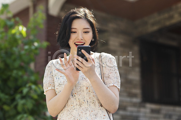 즐거움 20대 성인 성인여자한명만 여자 한국인 한명 JPG 앞모습 포토 거리 들기 미소(표정) 상반신 서기 스마트폰 싱글라이프 야외 여름(계절) 우먼라이프 원피스 응시 인싸 주간 취업준비생