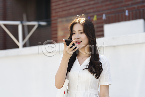 스마트 즐거움 20대 성인 성인여자한명만 여자 한국인 한명 JPG 앞모습 포토 거리 들기 미소(표정) 상반신 서기 스마트폰 싱글라이프 야외 에코백 여름(계절) 우먼라이프 음성인식 인싸 주간 캐주얼