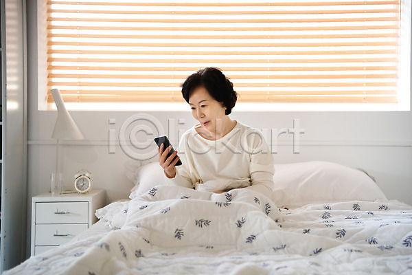 계획 60대 노년 노인여자한명만 사람 여자 한국인 한명 JPG 앞모습 포토 들기 상반신 스마트폰 실내 실버라이프 앉기 알람 응시 졸혼 침대 침실 확인
