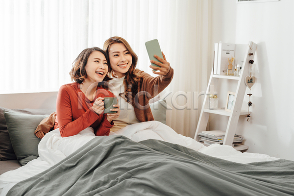 즐거움 함께함 휴식 동양인 두명 성인 성인여자만 여자 JPG 앞모습 포토 해외이미지 상반신 셀프카메라 스마트폰 실내 집콕 친구 침대 침실