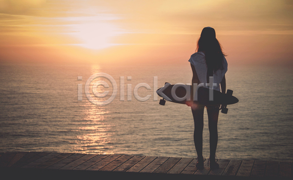 자유 행복 성인 성인여자한명만 여자 한명 JPG 뒷모습 포토 해외이미지 들기 서기 스케이터 스케이트보드 야외 여행 일몰 전신 태양 하늘 해변 햇빛