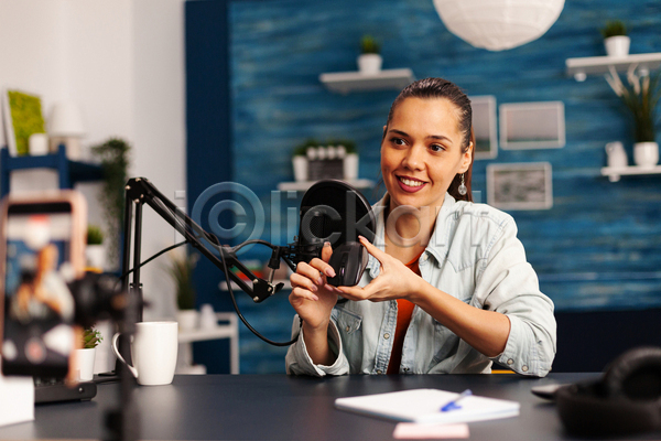 성인 성인여자한명만 여자 한명 JPG 앞모습 포토 해외이미지 공책 들기 마우스 마이크 방송 상반신 스마트폰 안내 유튜버 책상 촬영 촬영실 컵 파란색 헤드셋