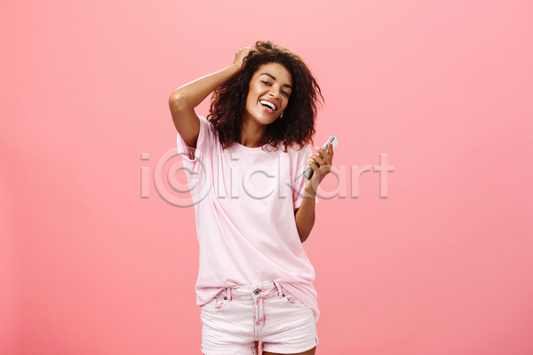 즐거움 성인 성인여자한명만 여자 한명 흑인 JPG 앞모습 포토 해외이미지 들기 분홍색 상반신 스마트폰 실내 웃음 음악감상