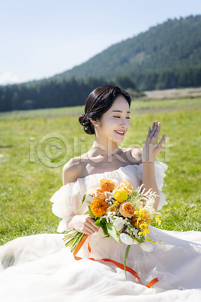 행복 20대 성인 성인여자한명만 여자 한국인 한명 JPG 앞모습 포토 결혼 결혼반지 들기 미소(표정) 부케 상반신 손짓 신부(웨딩) 앉기 야외 웨딩드레스 웨딩촬영 응시 제주도 주간 초원(자연)
