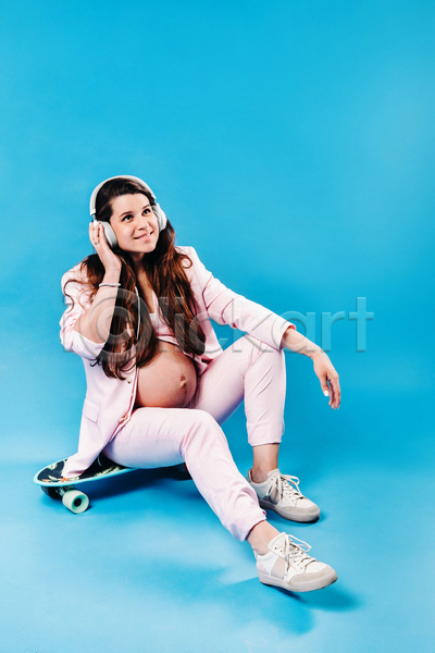성인 성인여자한명만 여자 한명 JPG 옆모습 포토 해외이미지 듣기 스케이트보드 실내 앉기 엄마 임산부 임신 전신 정장 파란배경 헤드셋