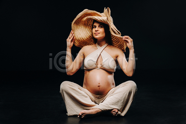 성인 성인여자한명만 여자 한명 JPG 앞모습 포토 해외이미지 가부좌 검은배경 밀짚모자 실내 앉기 응시 임산부 임신 잡기 전신 포즈