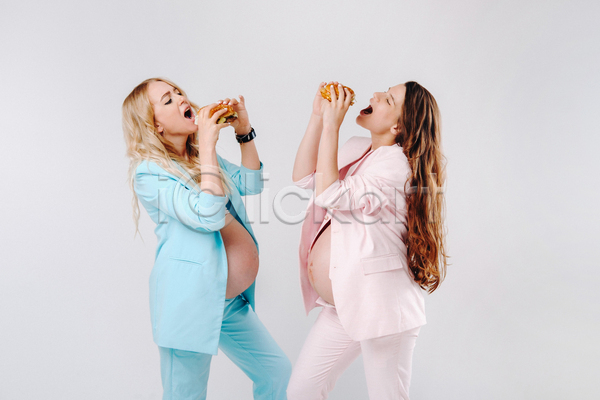 두명 성인 성인여자만 여자 JPG 옆모습 포토 해외이미지 들기 먹기 상반신 실내 엄마 임산부 임신 입벌림 정장 햄버거 흰배경
