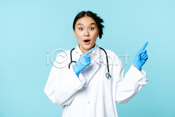 동양인 성인 성인여자한명만 여자 한명 JPG 앞모습 포토 해외이미지 가리킴 놀람 상반신 실내 의료진 의사 청진기 파란배경