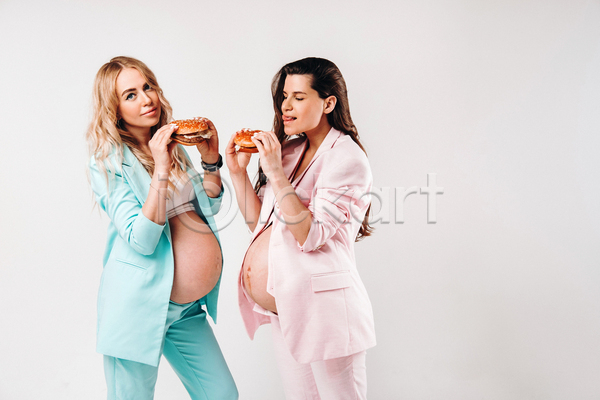 두명 성인 성인여자만 여자 JPG 옆모습 포토 해외이미지 들기 먹기 상반신 실내 엄마 응시 임산부 임신 정장 햄버거 흰배경