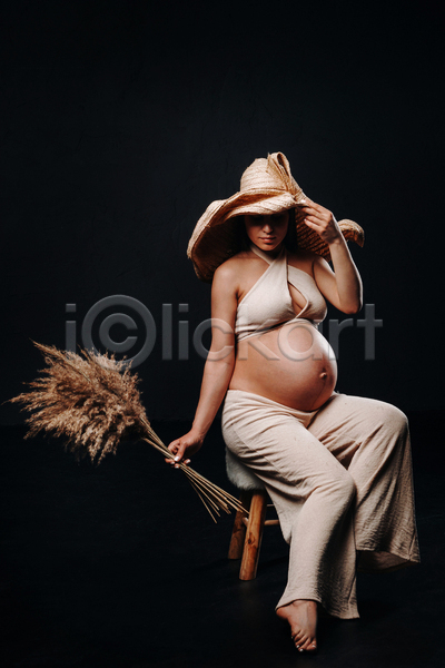 성인 성인여자한명만 여자 한명 JPG 앞모습 포토 해외이미지 검은배경 꽃다발 들기 밀짚모자 실내 앉기 의자 임산부 임신 전신 포즈