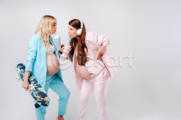 두명 성인 성인여자만 여자 JPG 포토 해외이미지 마시기 마주보기 상반신 스케이트보드 실내 엄마 응시 임산부 임신 정장 텀블러 허리손 헤드셋 흰배경