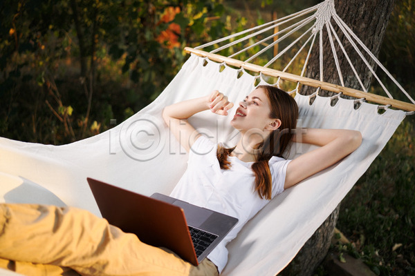 성인 성인여자한명만 여자 한명 JPG 앞모습 옆모습 포토 해외이미지 그림자 노트북 눕기 다리꼬기 상반신 야외 응시 자연 주간 해먹 햇빛