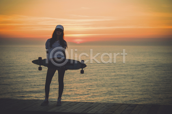 자유 청춘(젊음) 행복 성인 성인여자한명만 여자 한명 JPG 앞모습 포토 해외이미지 들기 스케이터 스케이트보드 여행 역광 일몰 전신 하늘 해변 햇빛