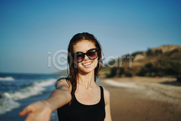 여유 휴식 성인 성인여자한명만 여자 한명 JPG 아웃포커스 앞모습 포토 해외이미지 바캉스 상반신 선글라스 손뻗기 야외 여름(계절) 여름휴가 웃음 주간 해변