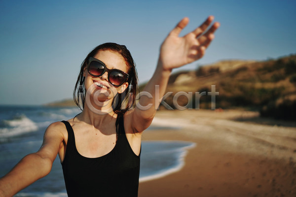 여유 휴식 성인 성인여자한명만 여자 한명 JPG 아웃포커스 앞모습 포토 해외이미지 미소(표정) 바캉스 상반신 선글라스 손뻗기 야외 여름(계절) 여름휴가 주간 해변