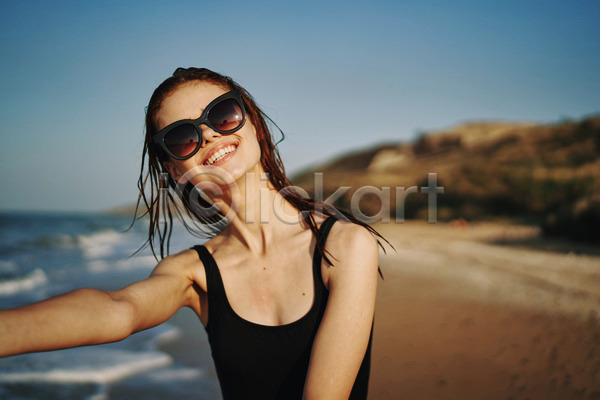여유 휴식 성인 성인여자한명만 여자 한명 JPG 아웃포커스 앞모습 포토 해외이미지 미소(표정) 바캉스 상반신 선글라스 손뻗기 야외 여름(계절) 여름휴가 주간 해변