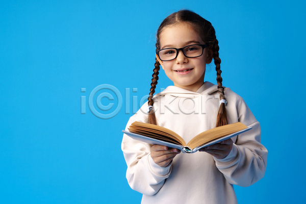 소녀(어린이) 소녀한명만 어린이 여자 한명 JPG 앞모습 포토 해외이미지 독서 들기 땋은머리 미소(표정) 상반신 실내 안경낌 양갈래머리 책 파란배경