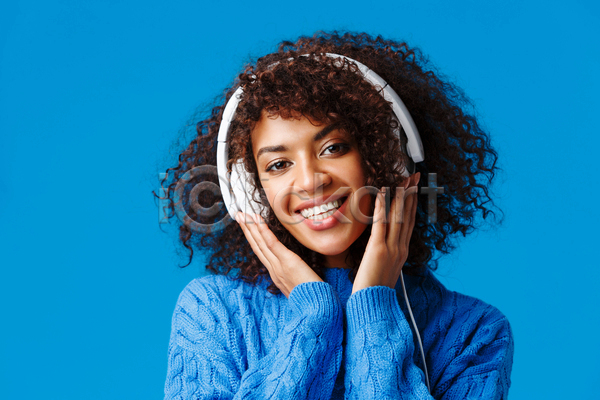 즐거움 성인 성인여자한명만 여자 한명 흑인 JPG 앞모습 포토 해외이미지 상반신 실내 웃음 음악감상 응시 파란색 헤드셋