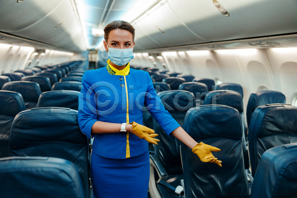 성인 성인여자한명만 여자 한명 JPG 앞모습 포토 해외이미지 가리킴 마스크착용 방역지침 비행기 상반신 생활방역 승객 승무원 여행 의자 장갑