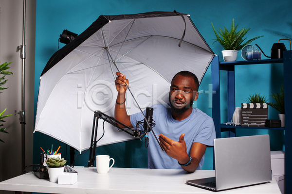 남자 성인 성인남자한명만 한명 JPG 앞모습 포토 해외이미지 노트북 들기 마이크 반사판 방송 상반신 선반 안내 우산 유튜버 책상 촬영 촬영실 컵 파란색 화초
