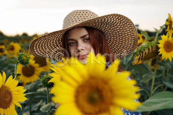 성인 성인여자한명만 여자 한명 JPG 소프트포커스 앞모습 포토 해외이미지 꽃밭 미소(표정) 밀짚모자 상반신 야외 여름(계절) 일몰 주간 풍경(경치) 해바라기