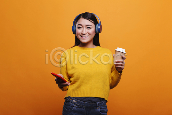 즐거움 동양인 성인 성인여자한명만 여자 한명 JPG 앞모습 포토 해외이미지 노란색 노래감상 들기 상반신 실내 웃음 주황색 커피 헤드셋