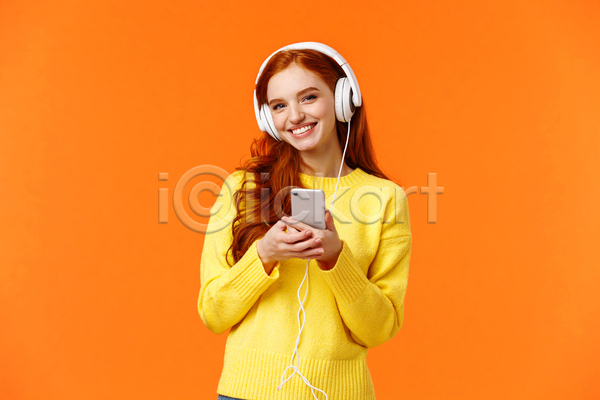 즐거움 성인 성인여자한명만 여자 한명 JPG 앞모습 포토 해외이미지 노란색 노래감상 들기 상반신 스마트폰 실내 웃음 주황색 헤드셋
