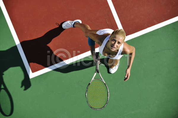 성인 성인여자한명만 여자 한명 JPG 앞모습 포토 하이앵글 해외이미지 그림자 들기 서기 야외 올려보기 웃음 전신 주간 테니스 테니스라켓 테니스선수 테니스장