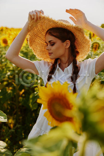 성인 성인여자한명만 여자 한명 JPG 소프트포커스 앞모습 포토 해외이미지 꽃밭 미소(표정) 밀짚모자 상반신 손들기 야외 여름(계절) 주간 풍경(경치) 해바라기