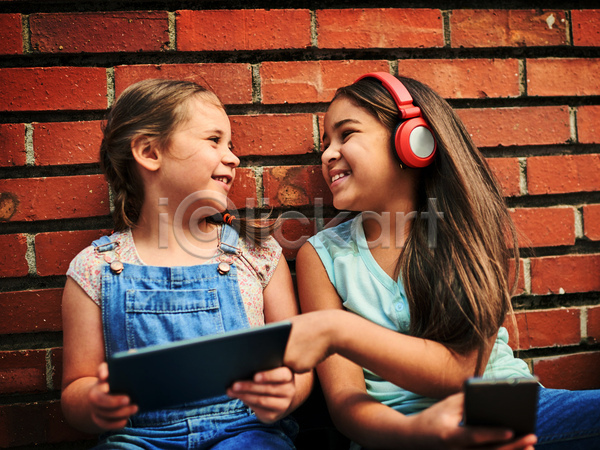 우정 즐거움 함께함 두명 소녀(어린이) 소녀만 어린이 여자 JPG 앞모습 포토 해외이미지 들기 마주보기 상반신 야외 웃음 주간 친구 태블릿 헤드셋