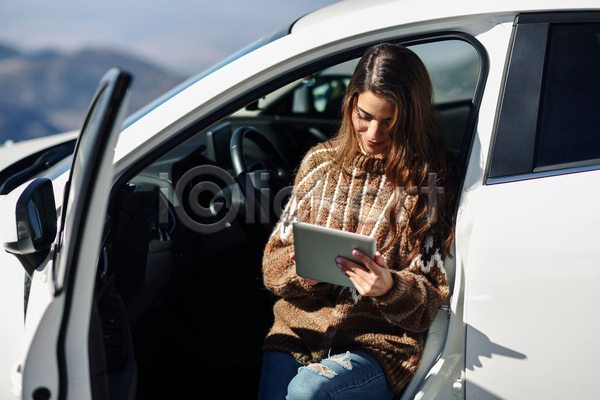 성인 성인여자한명만 여자 한명 JPG 아웃포커스 앞모습 포토 해외이미지 걸터앉기 겨울 들기 상반신 스웨터 야외 응시 자동차 주간 태블릿