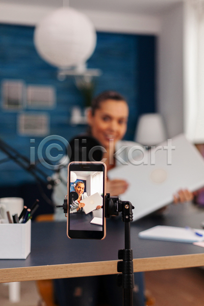 성인 성인여자한명만 여자 한명 JPG 앞모습 포토 해외이미지 들기 마이크 방송 상반신 스마트폰 유튜버 책상 촬영 촬영실 파란색