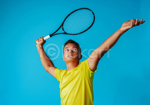 남자 성인 성인남자한명만 한명 JPG 옆모습 포토 해외이미지 들기 상반신 서브 손뻗기 실내 올려보기 응시 테니스 테니스라켓 테니스선수 파란배경