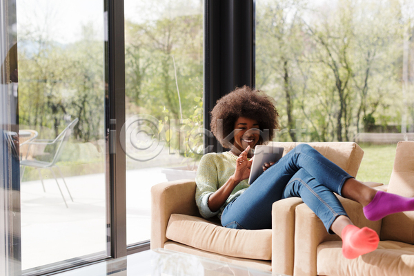 여유 휴식 성인 성인여자한명만 여자 한명 흑인 JPG 앞모습 포토 해외이미지 기댐 눕기 들기 소파 실내 앉기 앳홈라이프 웃음 전신 집콕 창가 태블릿