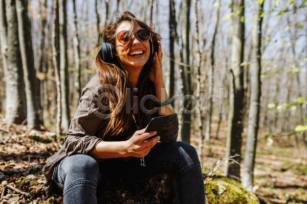 즐거움 휴식 성인 성인여자한명만 여자 한명 JPG 아웃포커스 앞모습 포토 해외이미지 들기 상반신 선글라스 앉기 야외 웃음 음악감상 주간 헤드셋