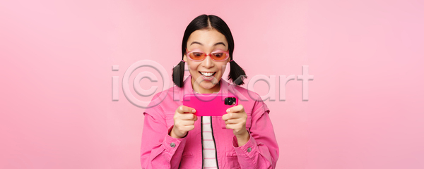 동양인 성인 성인여자한명만 여자 한명 JPG 포토 해외이미지 들기 분홍색배경 상반신 서기 선글라스 스마트폰 응시