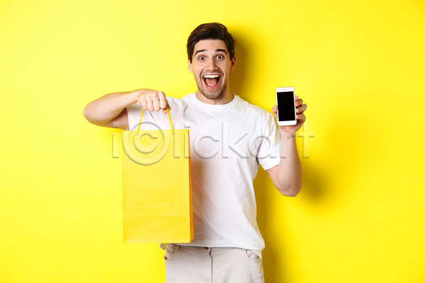 집중 남자 서양인 성인 성인남자한명만 한명 JPG 앞모습 포토 해외이미지 노란색 놀람 들기 보여주기 사각형 상반신 쇼핑 쇼핑백 스마트폰 주목 프레임