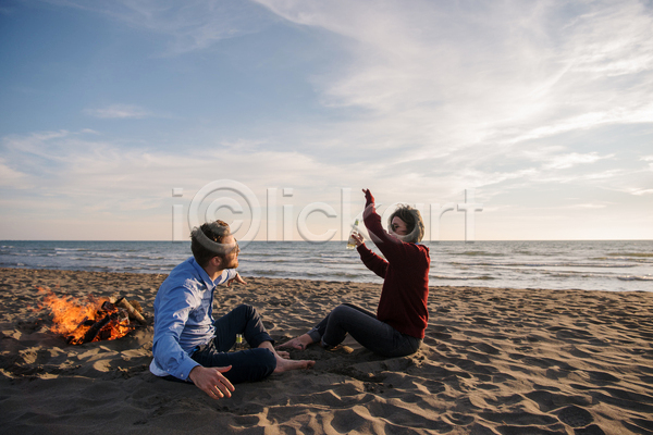 즐거움 함께함 남자 두명 성인 성인만 여자 JPG 옆모습 포토 해외이미지 들기 마주앉기 맥주병 모닥불 야외 전신 주간 캠핑 커플 하늘 해변
