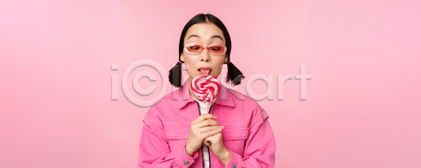 동양인 성인 성인여자한명만 여자 한명 JPG 포토 해외이미지 들기 막대사탕 먹기 분홍색배경 상반신 서기 선글라스